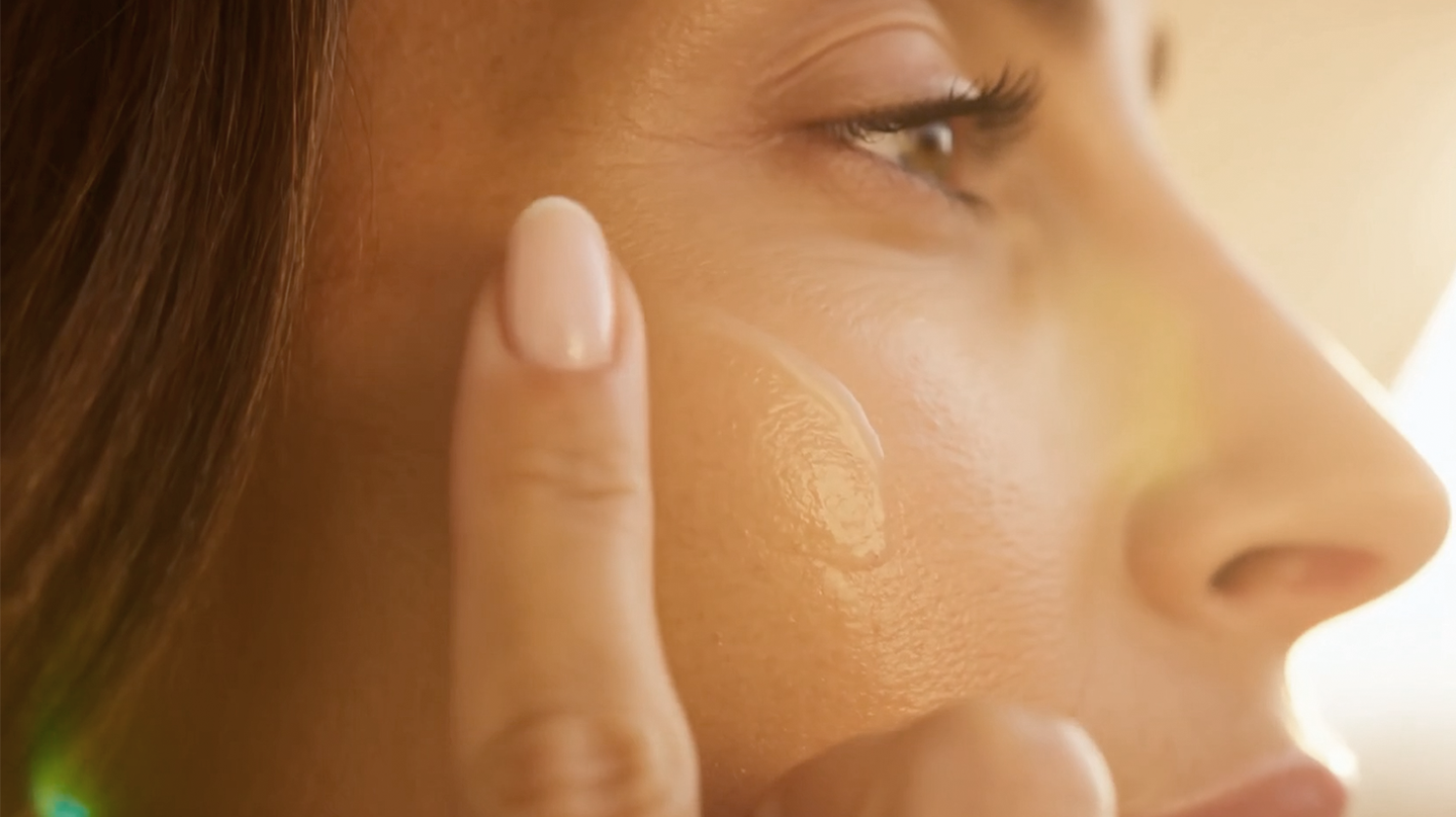 Close up of a women applying cream to her cheek