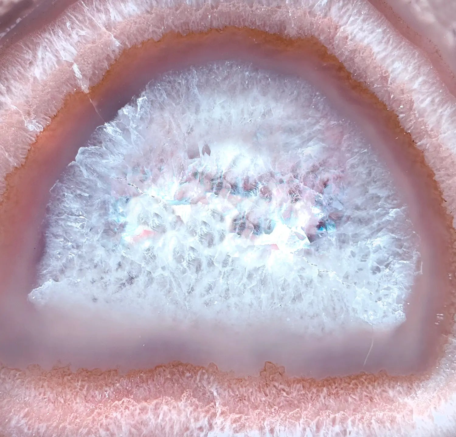 Close-up of a geode with a crystal inside, surrounded by pinkish rock.