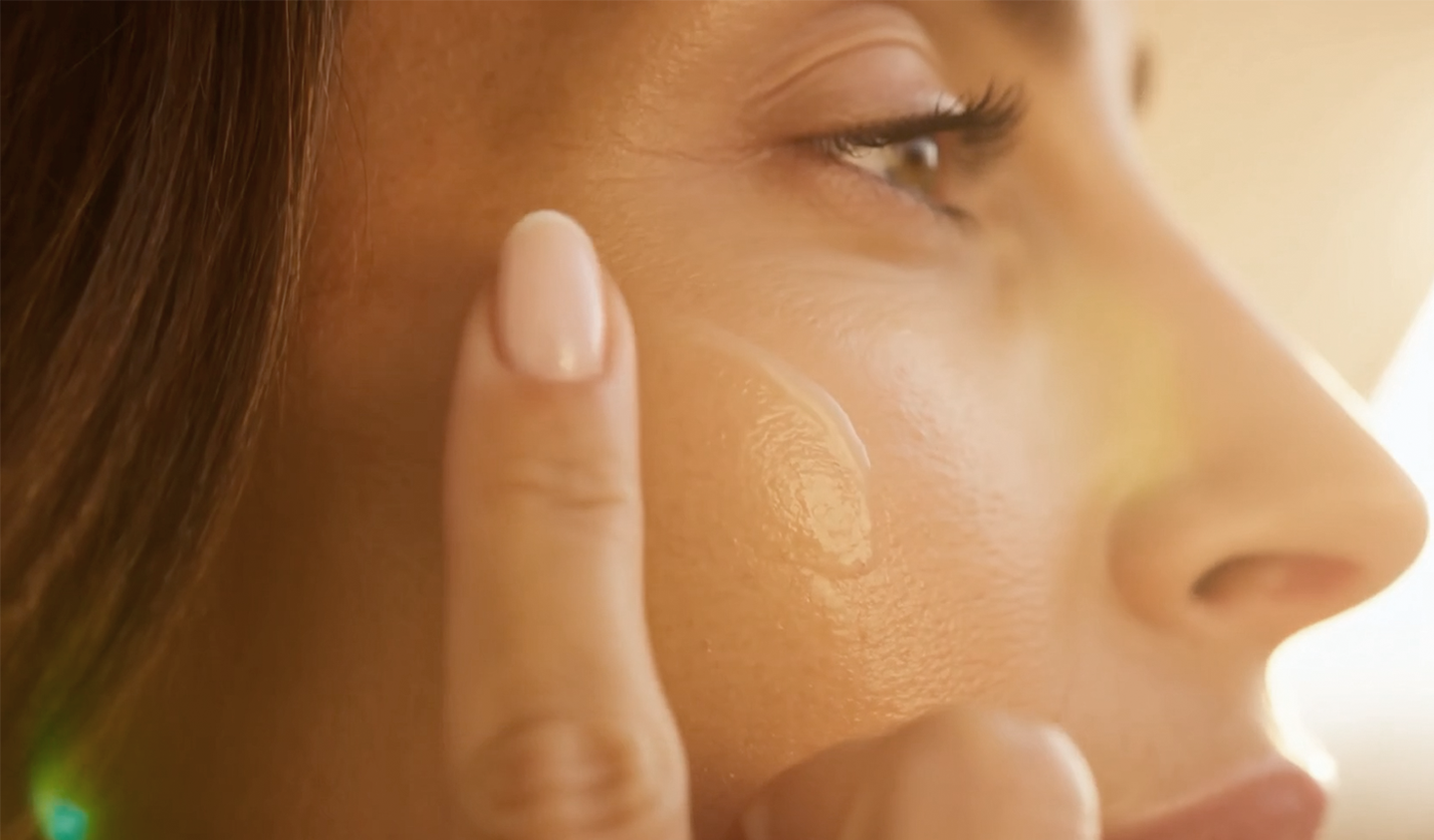 Close up of a women applying cream to her cheek