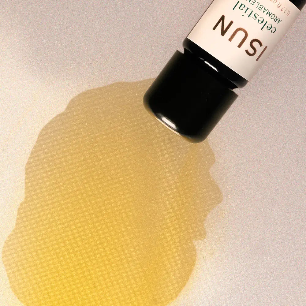 Bottle of ISUN essential oil with a yellow droplet on a light background