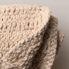 Close-up of a beige knitted face cloth with a neutral background