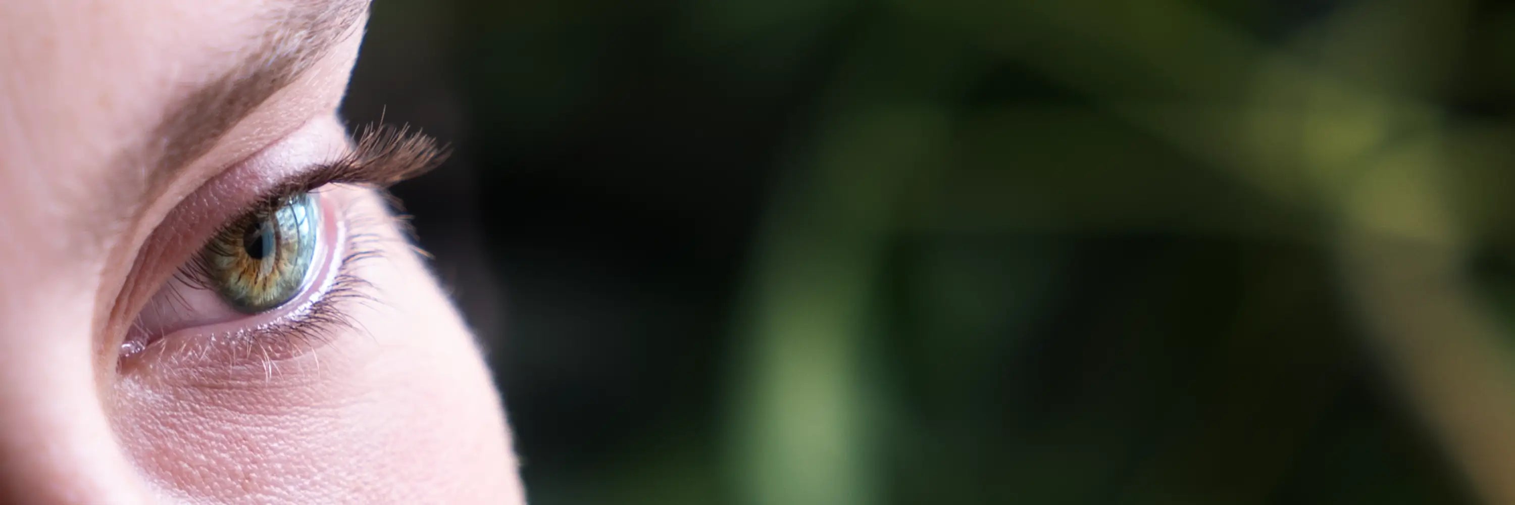 Close-up of a person's eye with a blurred green background