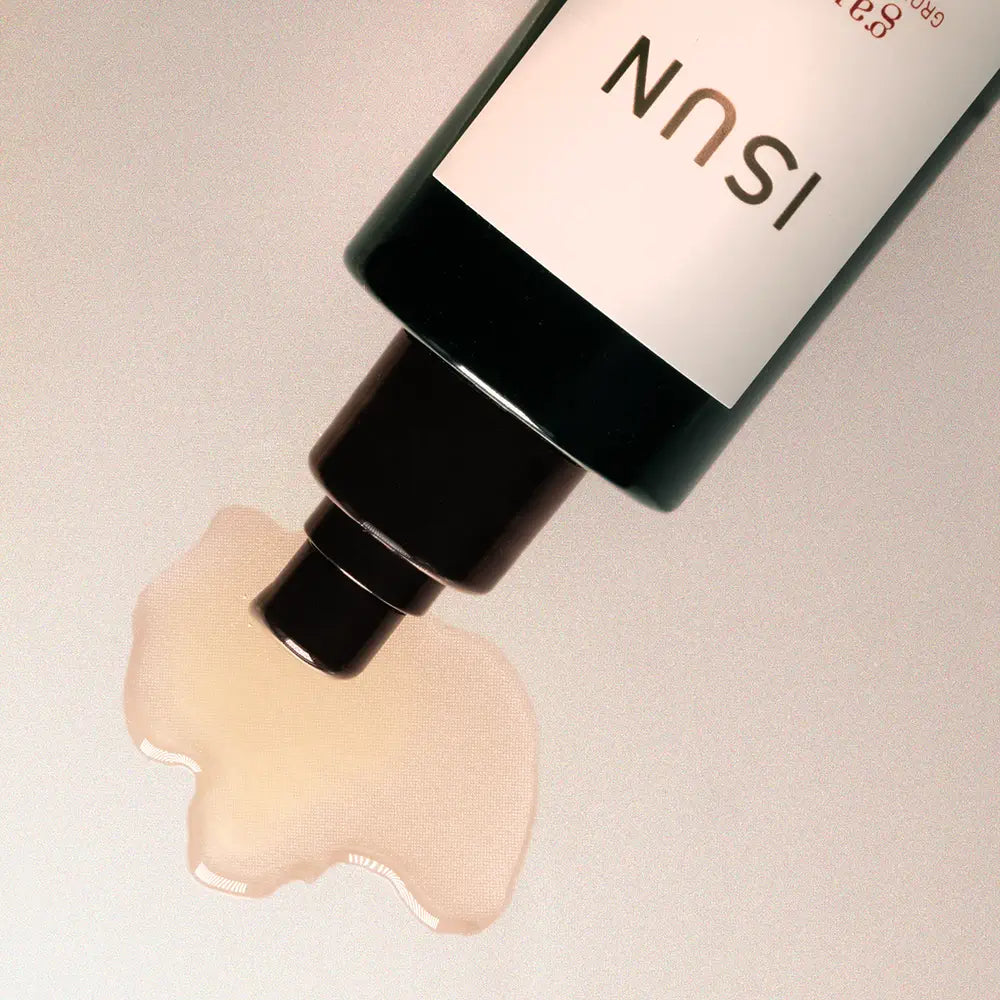 Cosmetic bottle with a pump dispensing oil on a neutral background