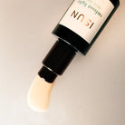 Cosmetic bottle with applicator on a neutral background