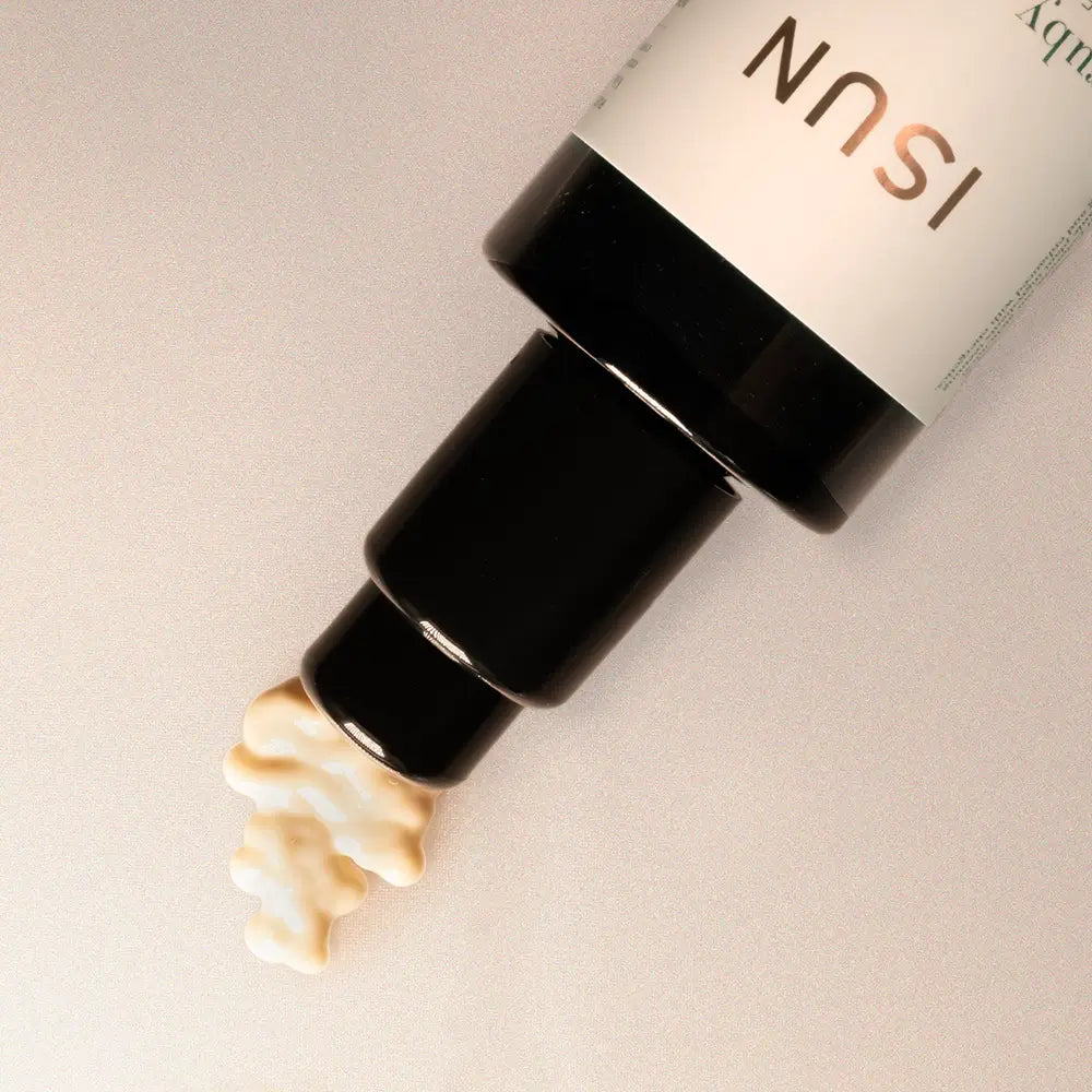 Cosmetic bottle with cream being squeezed out on a neutral background