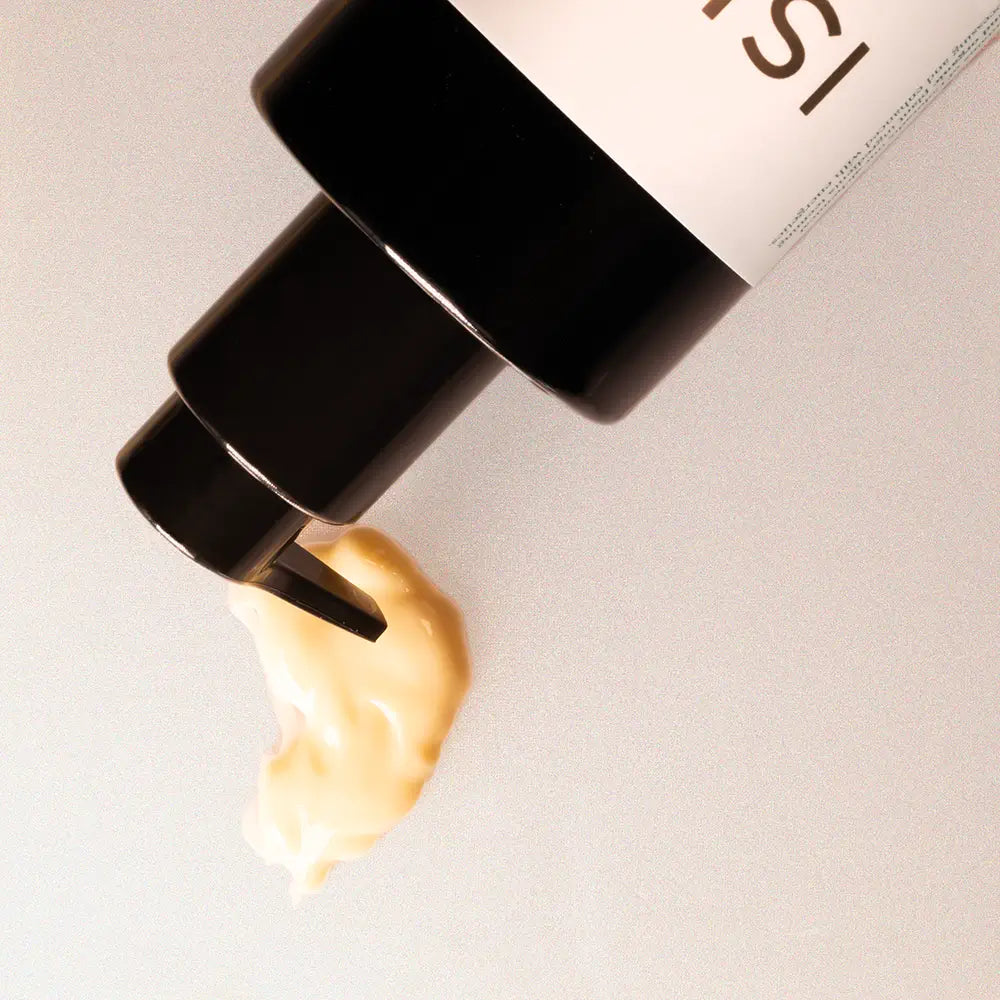 Cosmetic bottle with a swatch of cream on a neutral background