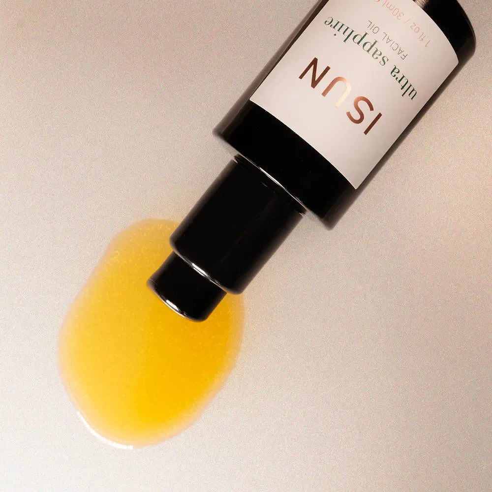 Skincare serum bottle with yellow liquid on a beige background