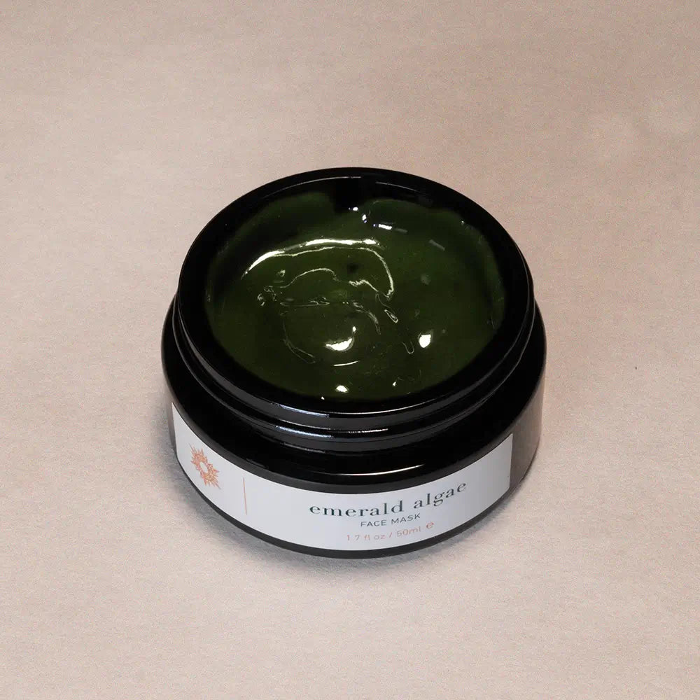 Jar of emerald algae face mask on a beige background