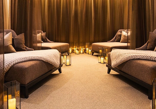 Luxury spa room with massage beds, candles, and draped curtains.